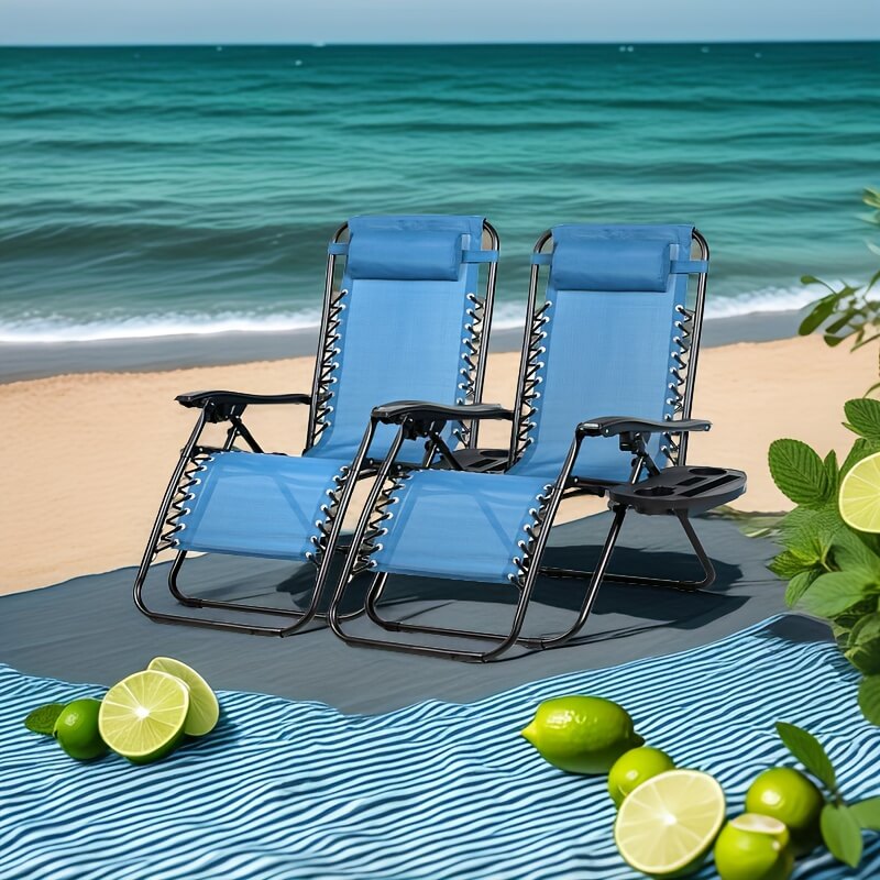 Two blue lounge chairs on a beach with limes and a blue towel.