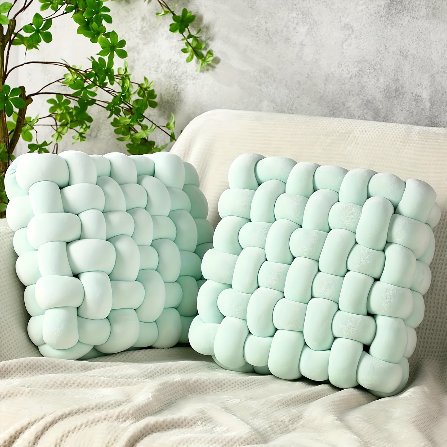 Two light blue woven pillows on a beige sofa with a neutral background